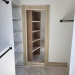 Light wood cased opening to walk-in closet with jamb and trim installed, unpainted raw wood finish.