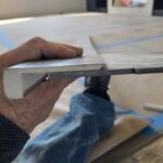 Trim piece being fitted and tested during installation; close-up of carpentry work in progress.