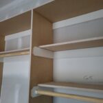 Face-frame closet shelving with painted shelves, wood rod, and textured backing board—multi-tier installation.