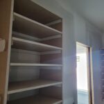 Multi-shelf built-in closet or storage unit with particle board shelves and support cleats, raw wood finish ready for paint.