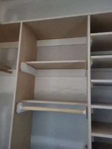 Unfinished closet shelving with particle board shelves, wood cleats, and hanging rod installed