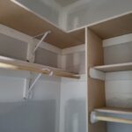 Closet shelving and hanging rods installed with white brackets, ready for paint.
