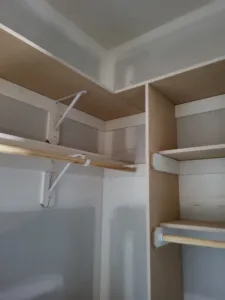 White closet shelf and rod bracket installed at an inside corner, crown molding above.