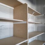 Multiple closet shelves with particle-board bullnose shelving and white metal brackets, raw unfinished wood ready for paint.