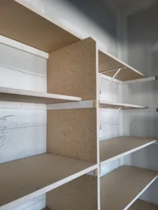 Unfinished closet shelving with particle board shelves and wood cleats, raw wood ready for paint
