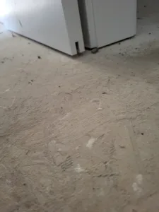White cabinet or appliance base sitting on unfinished concrete floor during construction.