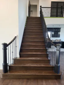 Straight staircase with dark stained wood treads, black metal balusters, and stained wood handrail.