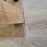 Baseboard-to-floor transition with stained wood baseboard and hardwood flooring meeting at a clean joint line.
