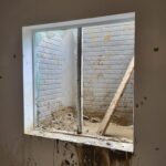 Window casing and jamb installed with painted trim and finished sill; window frame ready for glass or final details.