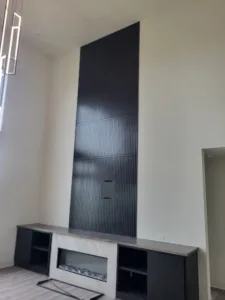 Black fluted panel accent wall above a fireplace with built-in cabinetry