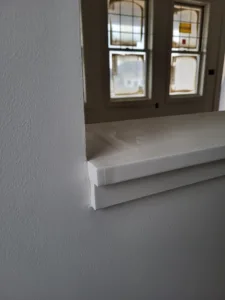 Painted white window sill with a bullnose edge below a divided light window