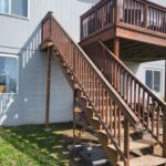 Multi-level exterior deck with wood stairs, railings, and balusters installed; stained finish visible.