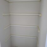 Four raw wood shelves with white brackets installed in closet, pre-paint stage.