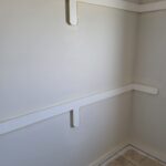 Two painted closet shelves with bracket supports installed in a finished closet opening.
