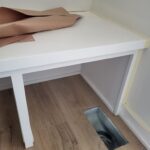 Finished white painted countertop shelf with wood frame and legs installed in closet space.