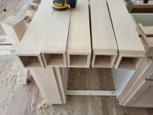 Unfinished cabinet boxes with open compartments sitting on a workbench, ready for hardware.