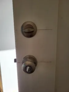 Deadbolt and entry door knob installed on a wood door edge, viewed at an angle