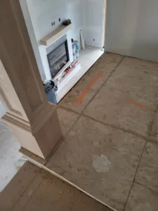 Raw wood mantel shelf mounted above a fireplace firebox with cement board surround, unfinished stage.
