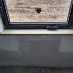 Finished wood window sill installed at interior window opening with black frame and white drywall surround.