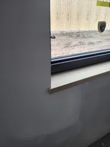 Sill corner detail at a window opening, gray wall surrounding the frame.