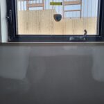 Dark wood window sill/stool installed at interior window opening, raw wood finish ready for paint.