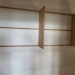 Closet shelving layout in progress with horizontal wood cleats and vertical divider, pencil marks for assembly.