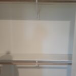 Closet shelving with stained wood rails and white support brackets installed on drywall.
