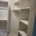 Painted closet shelving with multiple tiers, bullnose shelves, and hanging rod installed.