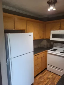 Finished kitchen with wood cabinets, tile backsplash, and appliances installed.