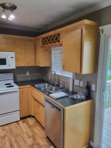 Finished kitchen with wood cabinets, wine rack, tile backsplash, and appliances installed.