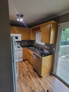 Kitchen with wood cabinets, tile backsplash, stainless dishwasher, and hardwood flooring, finished