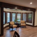 Finished sunroom with six cased windows, dark wood trim, and installed horizontal blinds throughout.