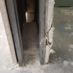 Rough door opening with metal frame and concrete floor during framing stage—no trim or finish installed.