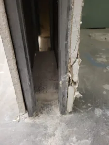 Rough door opening with a dark metal frame and bare concrete floor, no trim installed yet.