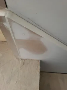 Primed triangular skirt board return at a stair corner, with a tan stain showing through the white primer