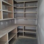Custom built-in closet shelving with open cubbies and countertop shelf, raw wood ready for finish.