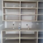 Custom built-in bookcase with open shelving compartments and integrated countertop, raw wood ready for paint or stain.