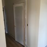 Primed hollow-core interior door installed with hinges and lockset prep, ready for paint.