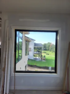 Finished white casing framing a black window unit, another building visible through glass.