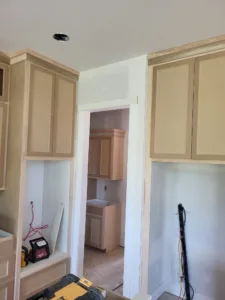 Hallway with raw wood cabinets flanking a cased opening between two rooms, unpainted trim stage.