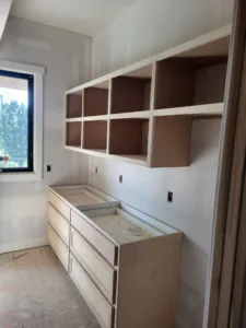 Unfinished built in cubby shelving over a drawer base, raw wood ready for paint