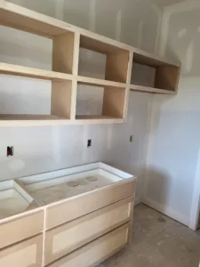 Unfinished built-in cabinetry with open shelving above and a raw wood drawer base below, ready for paint.
