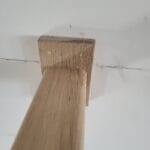 Close-up of a wood wall cap installation, showcasing the joinery and finish details at the top of a wall.