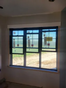 Large multi pane window with finished wood casing, dirt road and field visible outside.