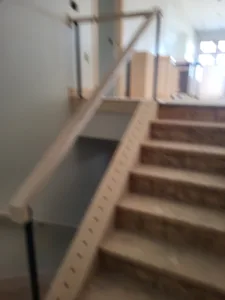 Unfinished staircase with raw wood treads and a single thin rail line, railing not yet installed