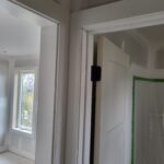 Bypass door slabs hung in finished frames with black hardware visible; ready for paint.