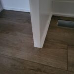 Painted baseboard installed at wall-to-floor junction with dark hardwood flooring.