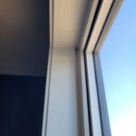 Painted exterior door casing on interior side of jamb, white finish against dark wall.
