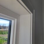 Painted interior casing and jamb on one side of exterior door opening, standard 6'8" height.