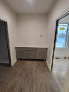 Vanity cabinet installed with drawer and door fronts, cased openings on both sides.